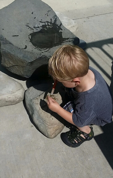 young boy at play painting on rocks with water