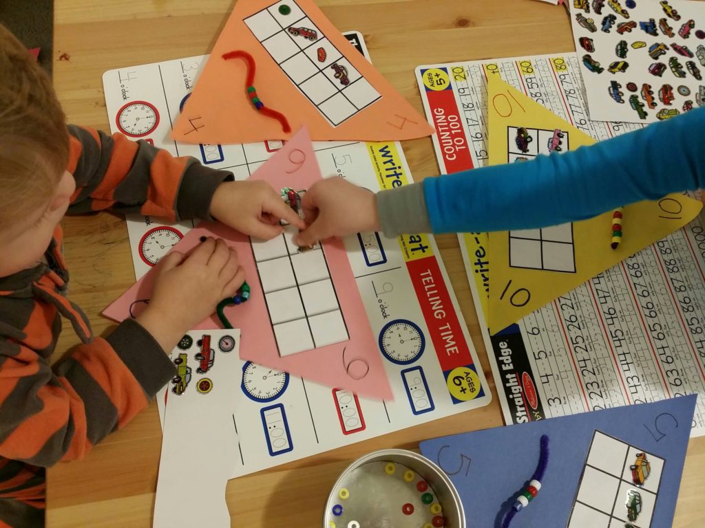 Brothers working together to count out 6 stickers for the ten frame
