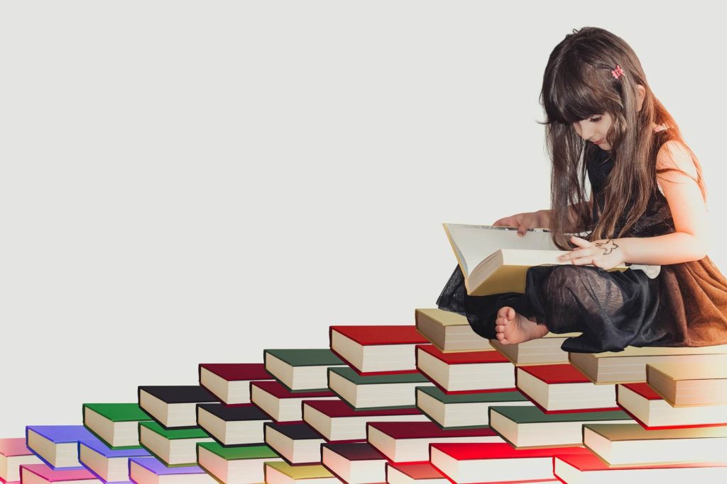 girl reading a book and sitting on a stack of books
